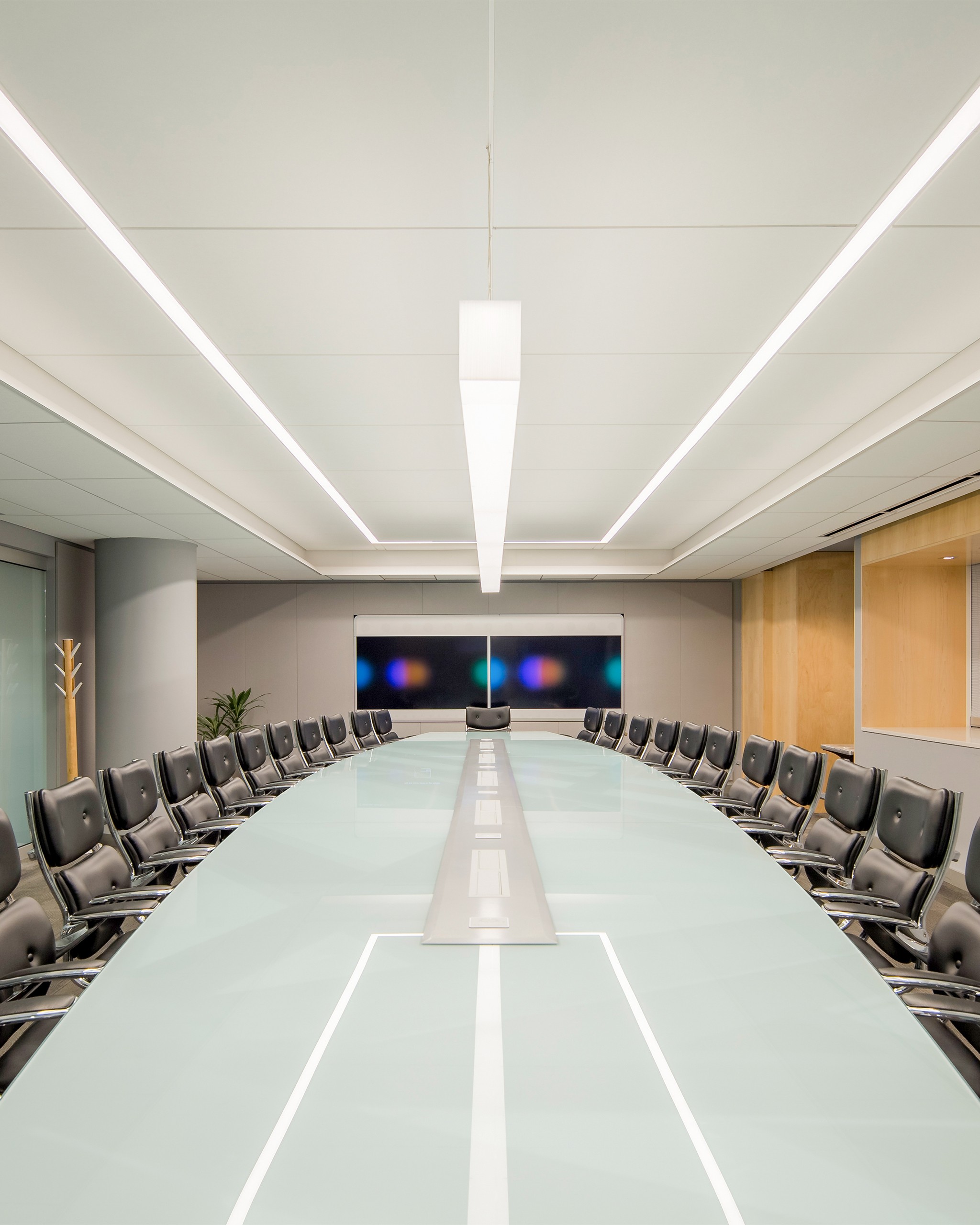 08_V2_8x10 Jacob K. Javits Convention Center Executive Board Room. Refurbished existing conference table, modernized and customized with artwork underlay and glass top. Surrounding storefront system features switchable privacy glass. Custom ceiling design and lighting controlled by state-of-the-art Lutron Palladiom system.